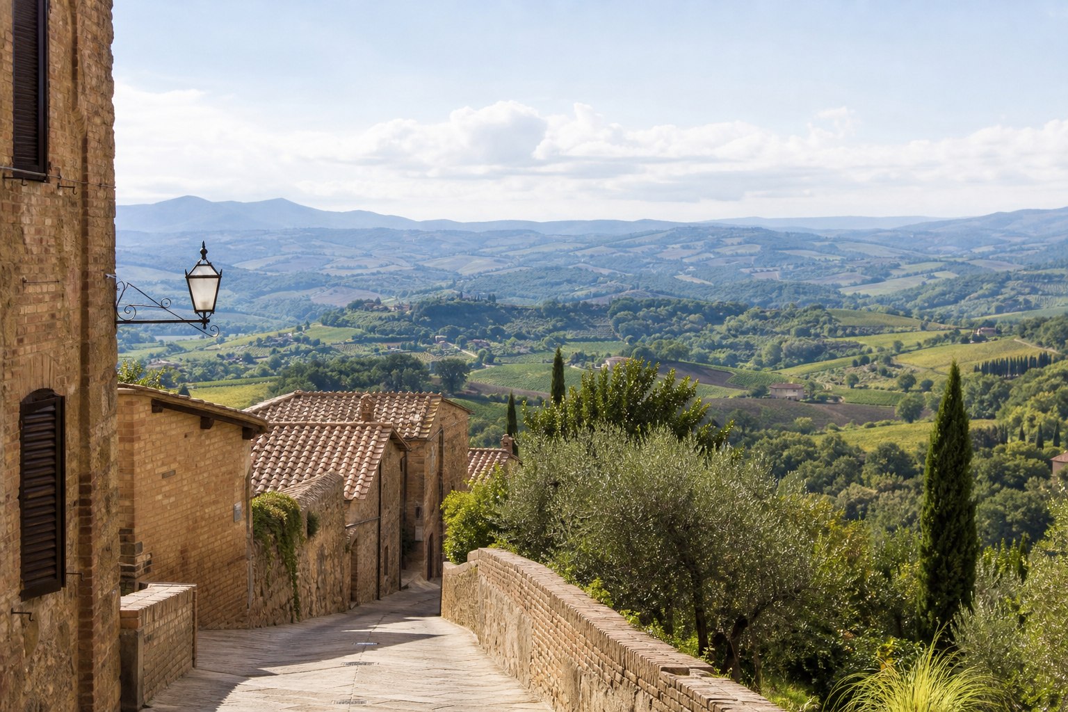 Uitzicht vanuit een Toscaans dorp over heuvels, olijfbomen en verspreide huizen